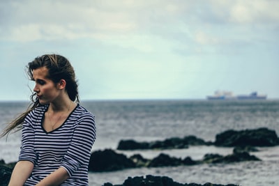 白天在海边拍摄黑白条纹V领肘袖衬衫的女人